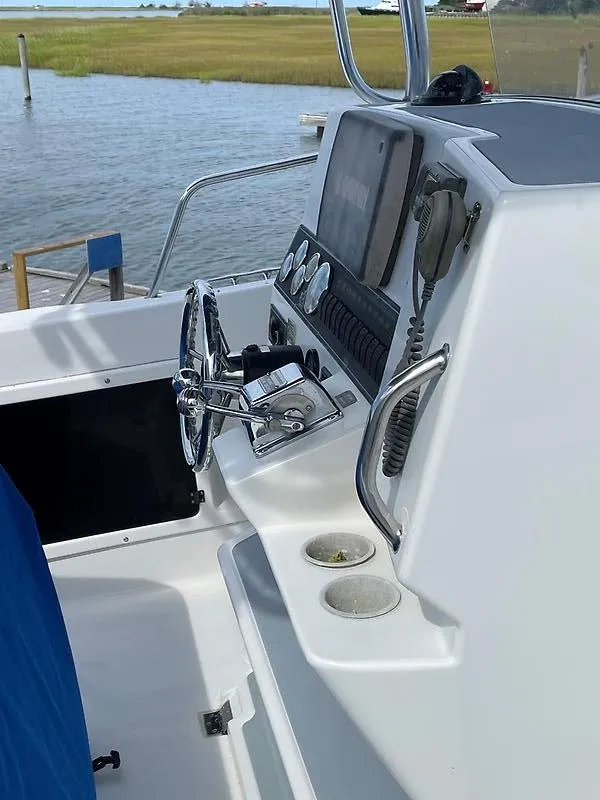 Slide: The Image of 2001 Shamrock 270 Open boat dashboard with steering wheel and controls, near water. - 19