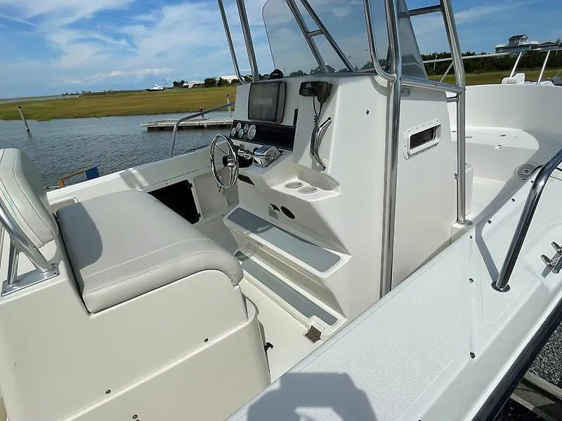 Slide: The Image of 2001 Shamrock 270 Open boat interior with steering console and seating, docked by a scenic waterway. - 24