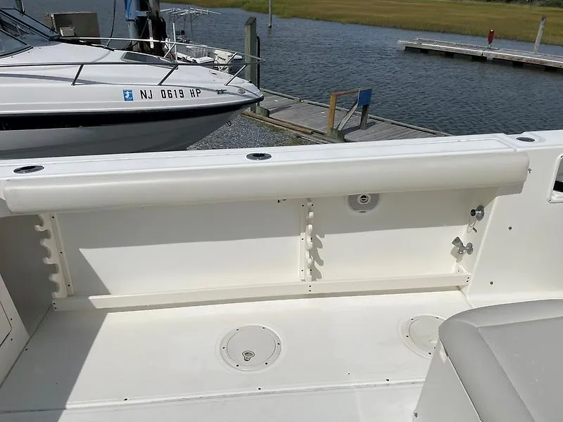 Slide: The Image of 2001 Shamrock 270 Open boat interior, featuring a clean deck and rod holders, docked by the water. - 39