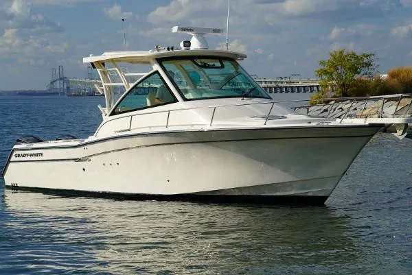 The Image of 2016 Grady-White Express 330 boat on calm water near a bridge and shoreline. - 0