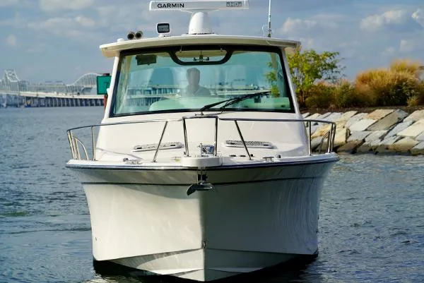 Slide: The Image of 2016 Grady-White Express 330 boat on water near rocky shoreline. - 2