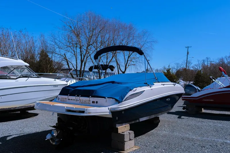Slide: The Image of 2013 Sea Ray 240 Sundancer boat on blocks, covered, with blue sky background. - 4