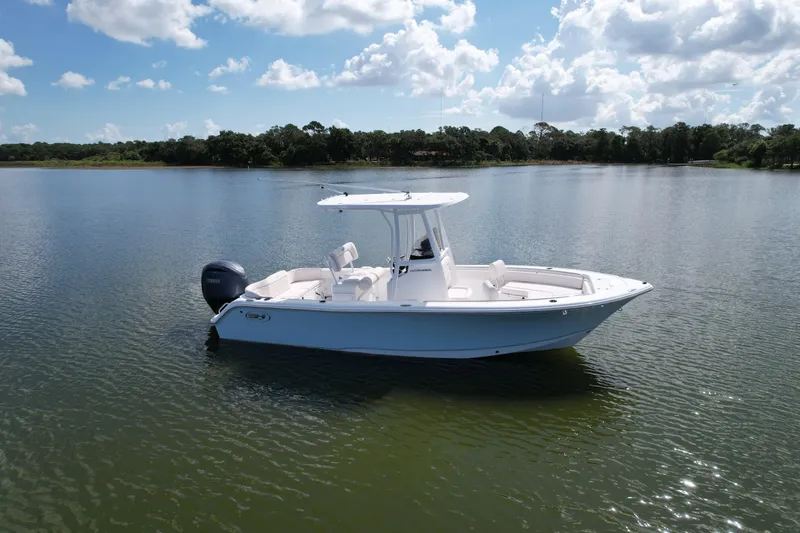 Slide: The Image of 2025 Sea Hunt Ultra 229 boat on calm lake under blue sky. - 2