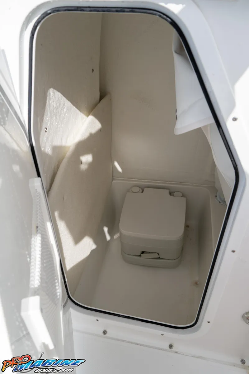 Slide: The Image of 2025 Sea Hunt Ultra 229 boat interior with compact marine toilet. - 24