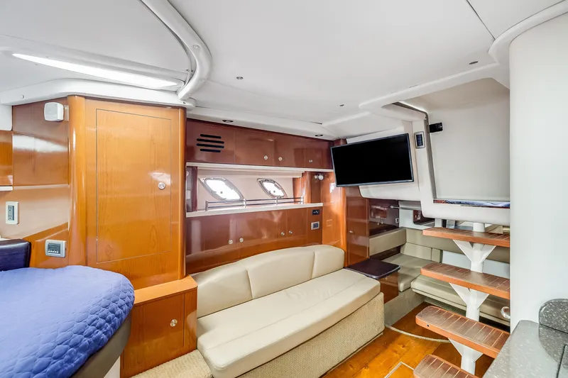Slide: The Image of 2014 Sea Ray 330 Sundancer cabin interior with wood finishes, sofa, and mounted TV. - 11