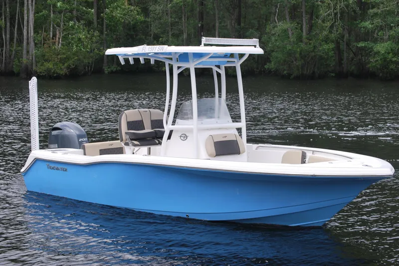 Slide: The Image of 2021 Tidewater 210 CC Adventure boat on calm water, featuring a blue hull and Yamaha engine. - 0