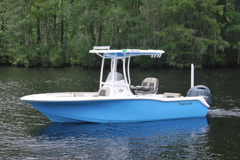 Slide: The Image of 2021 Tidewater 210 CC Adventure boat on a calm river with lush green trees. - 1