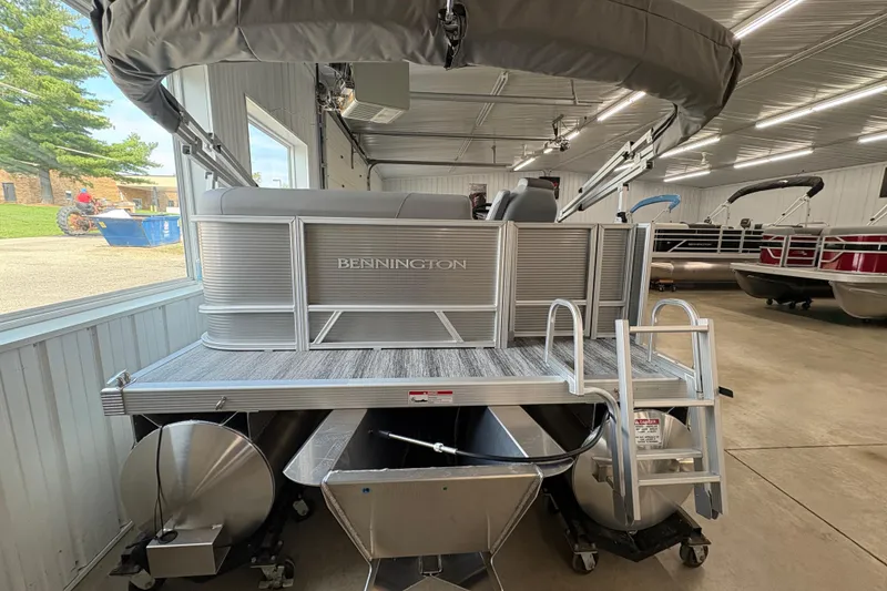 Slide: The Image of 2026 Bennington 168 SL Electric pontoon boat in showroom, rear view with ladder. - 4
