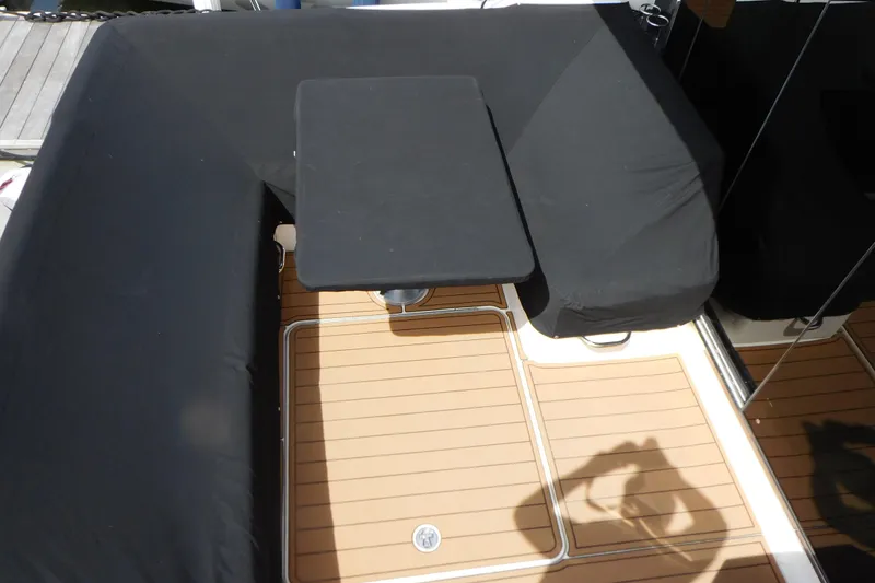 Slide: The Image of 2013 Sea Ray 510 Sundancer cockpit with black seating and table, teak flooring. - 16