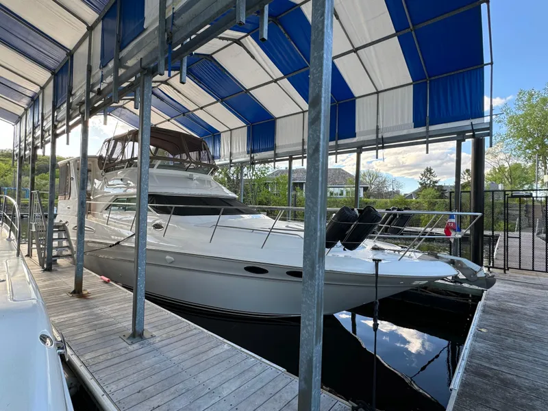 Slide: The Image of 2001 Sea Ray 420 Aft Cabin yacht docked under a blue and white canopy. - 4