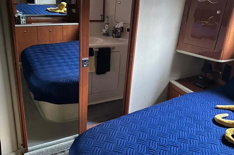Slide: The Image of Interior of 2001 Sea Ray 420 Aft Cabin with blue bedding and wooden cabinetry. - 59