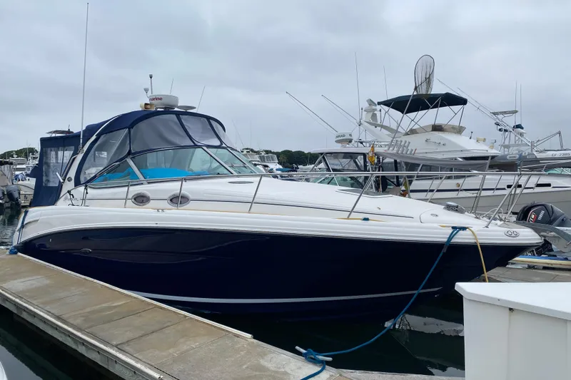 The Image of 2005 Sea Ray 300 Sundancer docked at marina, featuring sleek design and blue canopy. - 0