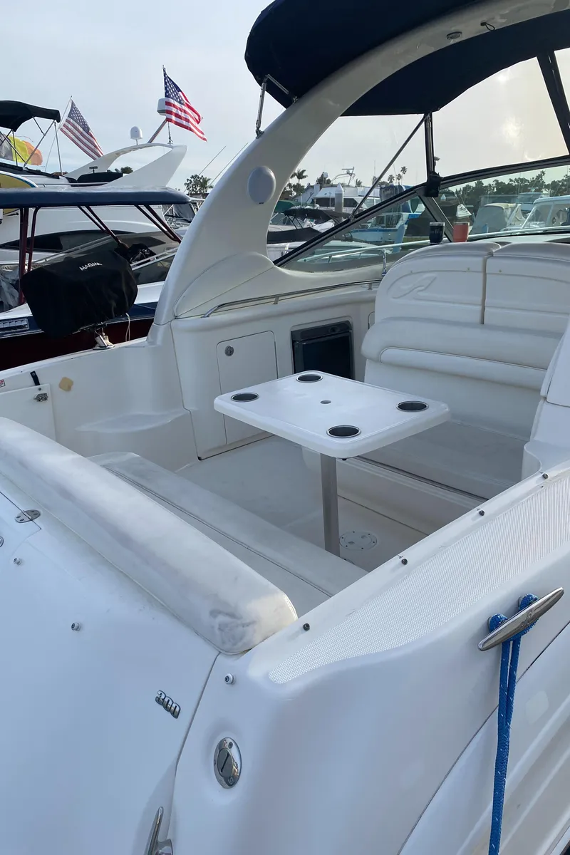 Slide: The Image of 2005 Sea Ray 300 Sundancer boat with seating area and table, docked at marina. - 12