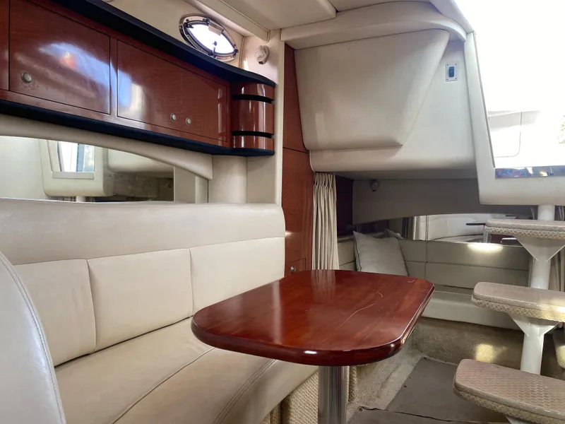 Slide: The Image of Interior of 2005 Sea Ray 300 Sundancer, featuring elegant seating and wooden table. - 13