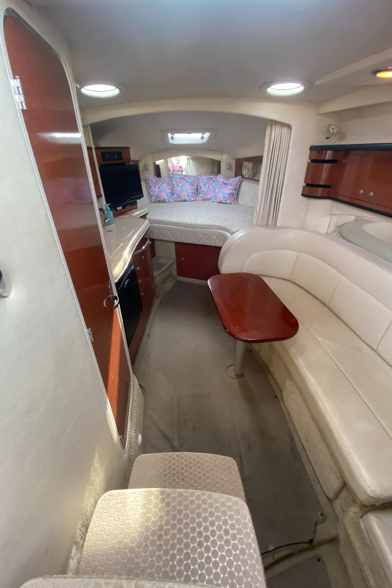 Slide: The Image of Interior of 2005 Sea Ray 300 Sundancer with seating, table, and cozy sleeping area. - 21