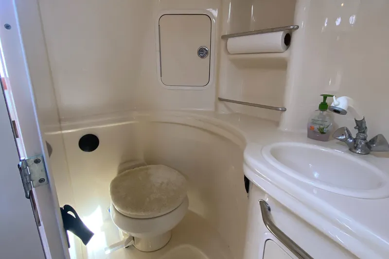 Slide: The Image of 2005 Sea Ray 300 Sundancer bathroom with toilet, sink, and storage shelves. - 22