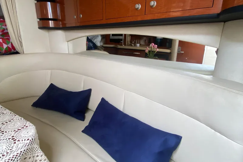 Slide: The Image of Interior of 2005 Sea Ray 300 Sundancer with white seating and blue cushions. - 29