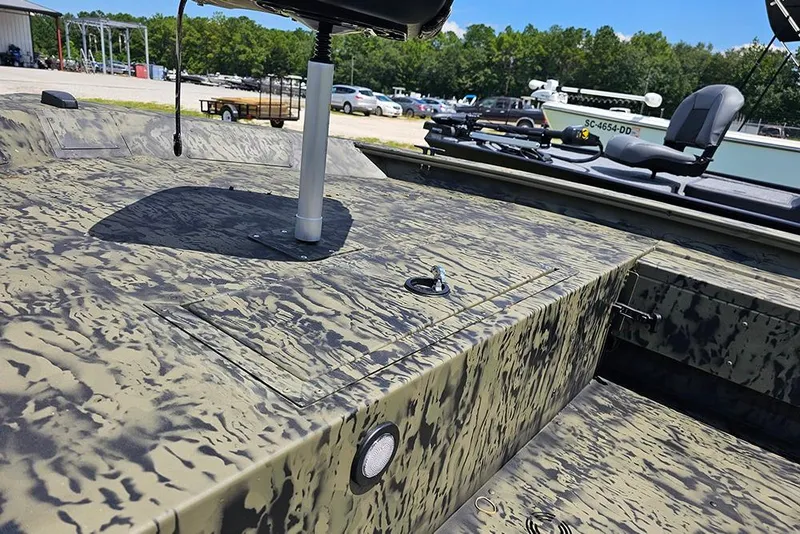 Slide: The Image of 2026 Tracker Grizzly 1654 T Sportsman boat with camouflage design in a parking area. - 15