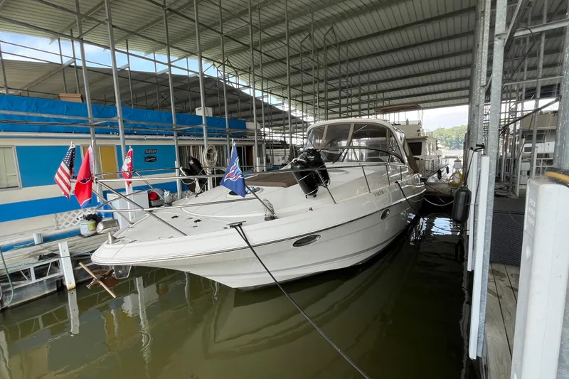 Slide: The Image of 2007 Regal 3760 IB Commodore yacht docked in a covered marina, adorned with flags. - 2