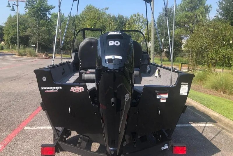 Slide: The Image of 2026 Tracker Pro Guide V-16 WT boat with Mercury 90 engine in a parking lot. - 2
