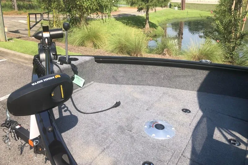 Slide: The Image of 2026 Tracker Pro Guide V-16 WT boat with Minn Kota trolling motor, parked near a pond. - 8