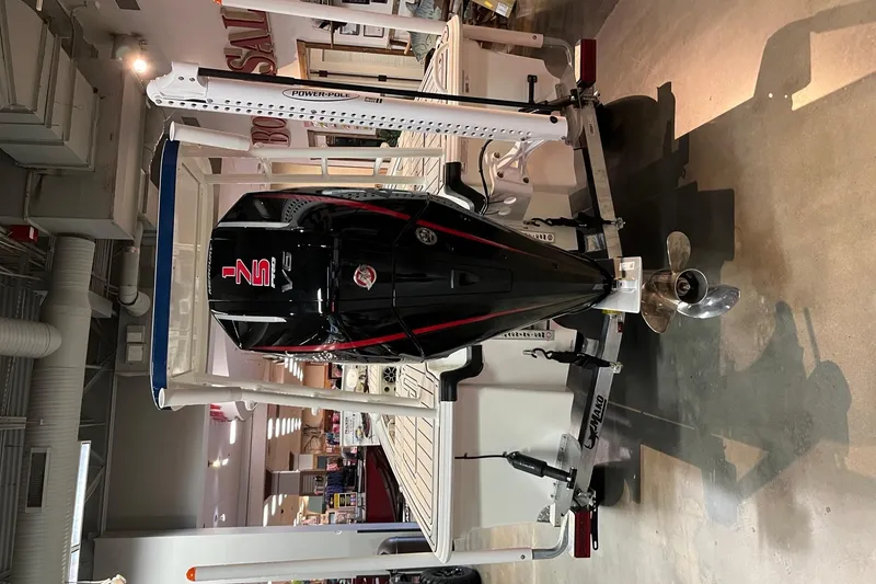 Slide: The Image of 2025 Mako 18 Pro Skiff Patriot Edition with powerful outboard motor in showroom. - 5