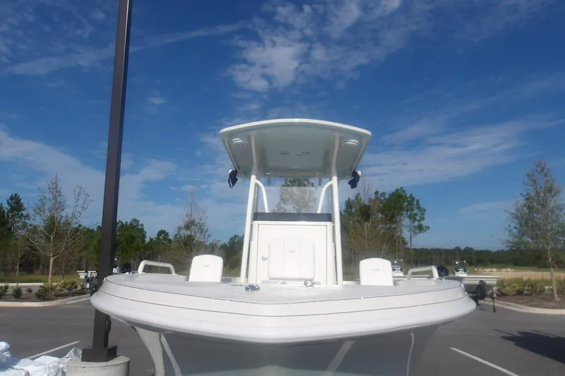 Slide: The Image of 2025 Ranger 2360 Bay boat under clear blue sky in a parking area. - 16