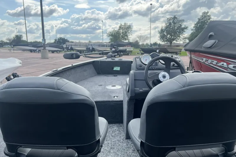 Slide: The Image of 2026 Tracker Super Guide V-16 SC boat interior with steering wheel and seats, parked outdoors. - 3