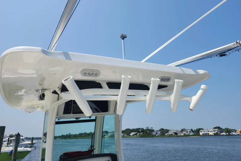 Slide: The Image of 2016 Boston Whaler 250 Outrage boat with rod holders and canopy, docked by the water. - 13