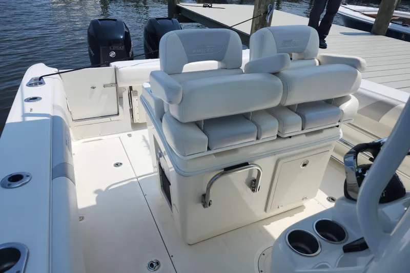 Slide: The Image of 2016 Boston Whaler 250 Outrage boat interior with seating and storage, docked by the water. - 6