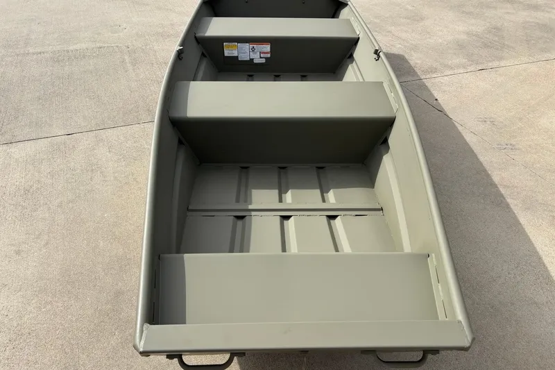 Slide: The Image of 2026 Tracker Grizzly 12 Jon boat, interior view, showcasing seating and storage on concrete surface. - 2