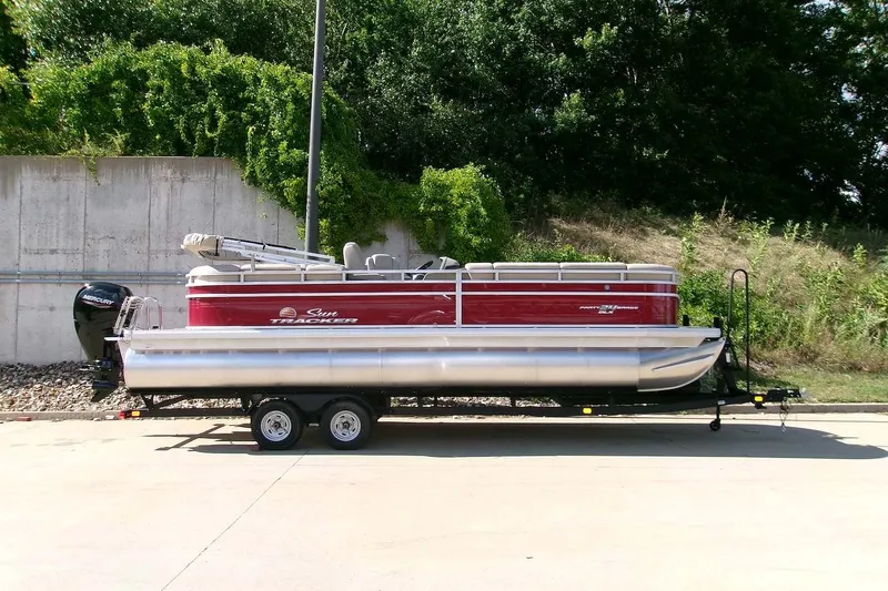 The Image of 2025 Sun Tracker Party Barge 24 DLX pontoon boat on trailer, parked outdoors. - 0