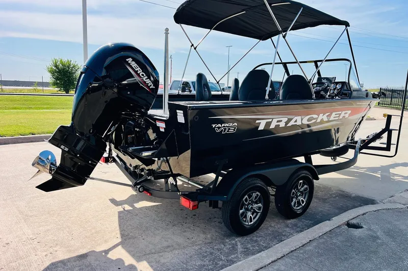 Slide: The Image of 2026 Tracker Targa V-18 Combo boat with Mercury engine on trailer, parked outdoors. - 6