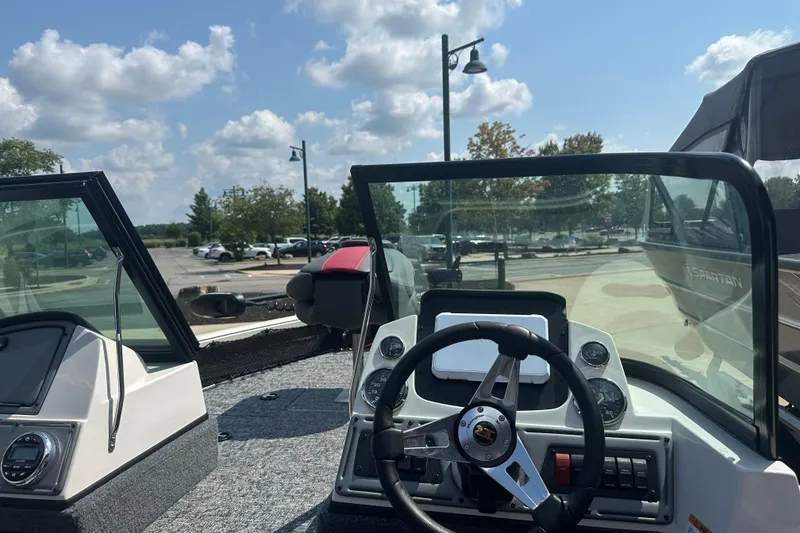 Slide: The Image of 2025 Ranger VS1682SC Reata boat dashboard with steering wheel and controls, parked outdoors. - 2