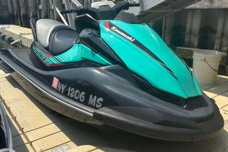 Slide: The Image of 2021 Kawasaki Jetski STX 160X in teal, docked on a platform. - 2