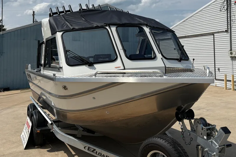 Slide: The Image of 2026 Lund 210 HG boat on trailer, parked outdoors, featuring sleek design and modern features. - 10