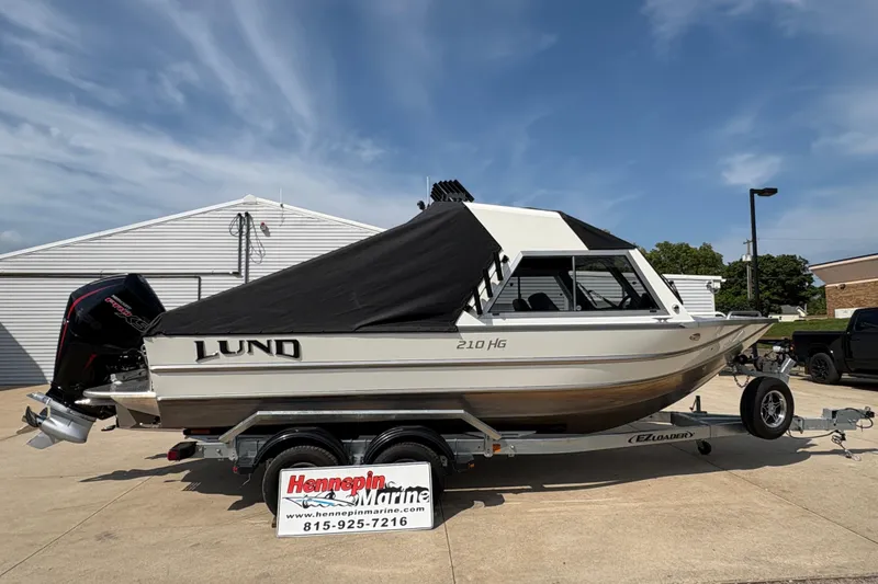 Slide: The Image of 2026 Lund 210 HG boat on trailer, covered, parked outdoors at Hennepin Marine. - 13