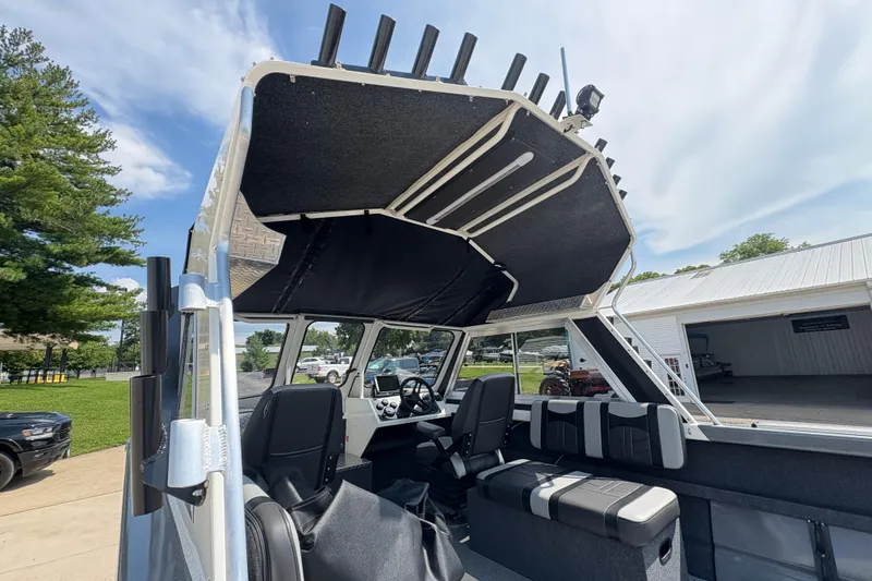 Slide: The Image of 2026 Lund 210 HG boat interior with seating and rod holders under a clear sky. - 15