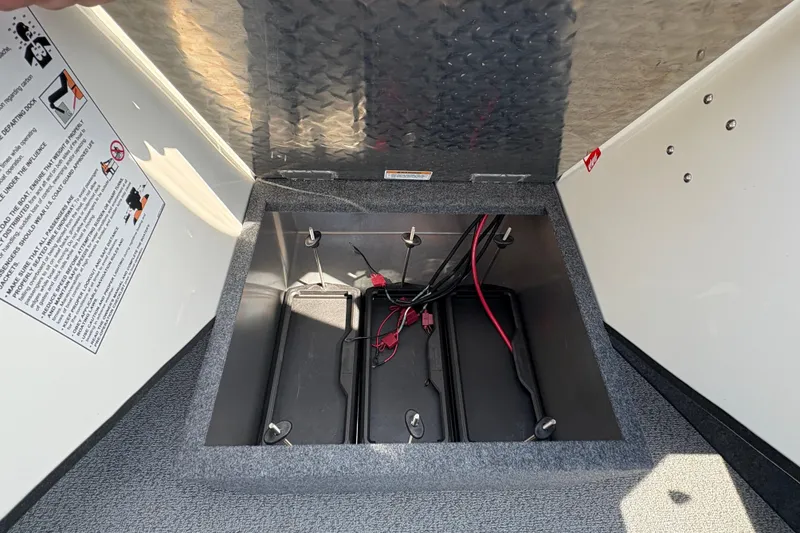 Slide: The Image of Open storage compartment in 2026 Lund 210 HG boat, showing wiring and battery slots. - 21