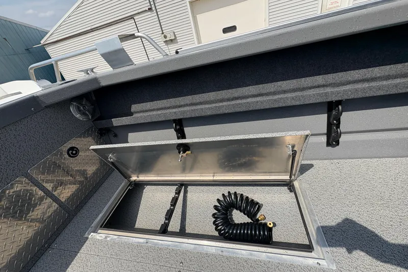 Slide: The Image of 2026 Lund 210 HG boat storage compartment with coiled hose on deck. - 34