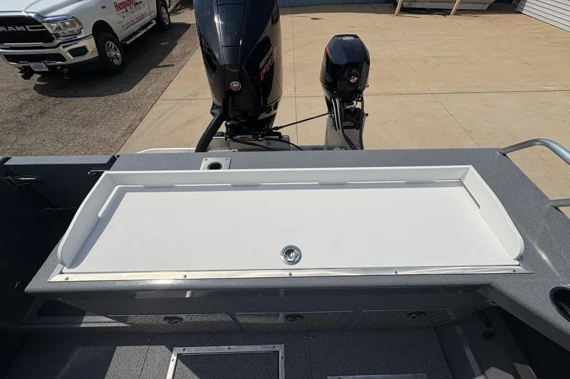 Slide: The Image of 2026 Lund 210 HG boat with dual outboard motors, parked beside a truck. - 38