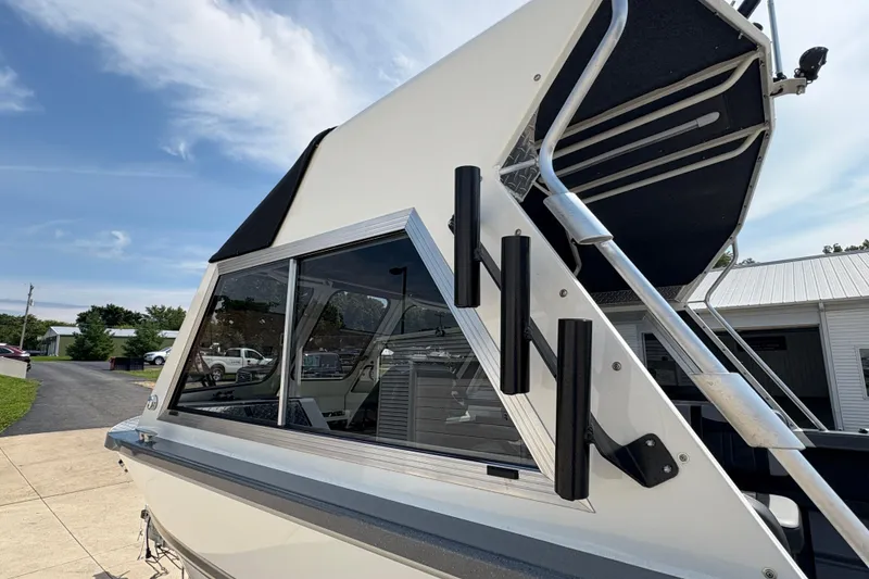 Slide: The Image of 2026 Lund 210 HG boat with sleek design and rod holders, parked outdoors. - 50