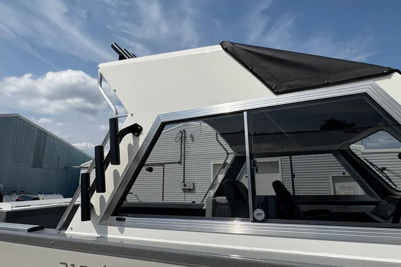 Slide: The Image of 2026 Lund 210 HG boat with sleek design and tinted windows under a blue sky. - 52