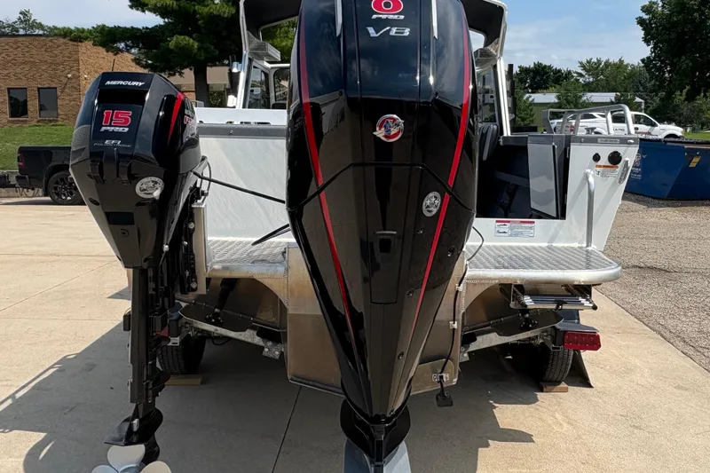 Slide: The Image of 2026 Lund 210 HG boat with dual Mercury outboard engines, parked outdoors. - 6