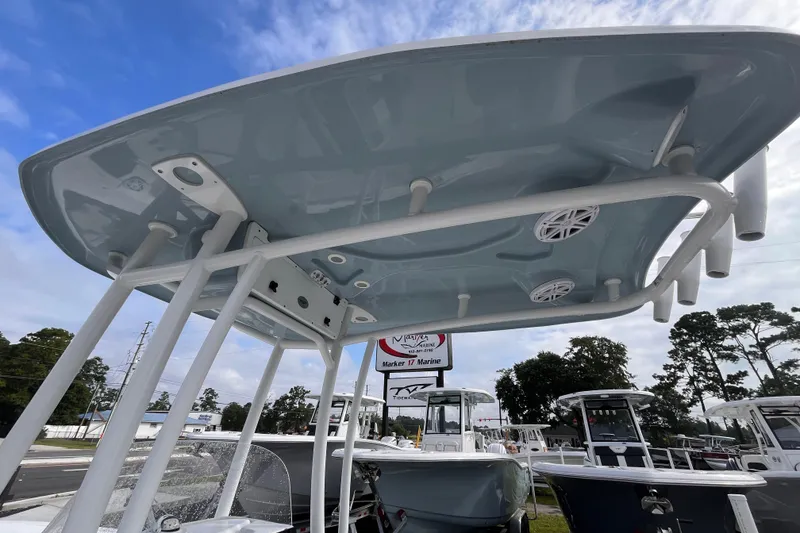 Slide: The Image of 2024 Tidewater 210 LXF boat with T-top and rod holders, displayed outdoors. - 14