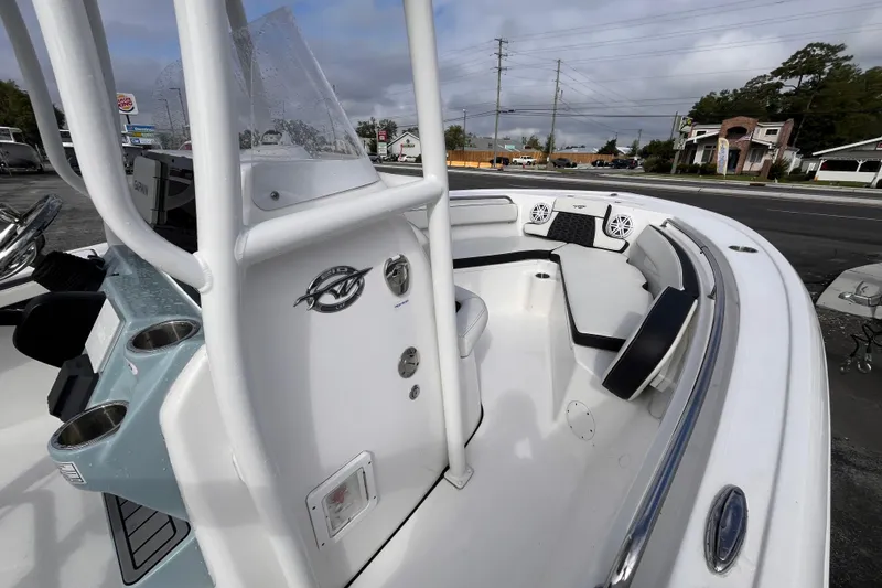 Slide: The Image of 2024 Tidewater 210 LXF boat interior with seating and console, parked outdoors. - 9