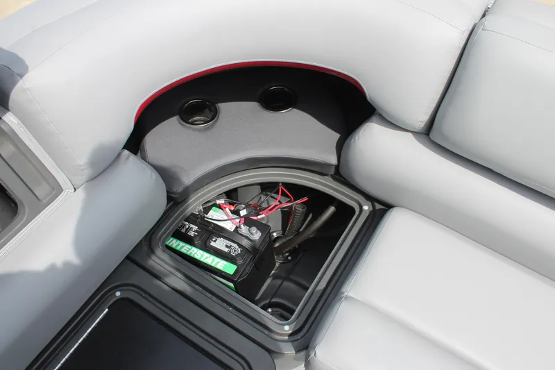 Slide: The Image of 2026 Sun Tracker Party Barge 20 DLX battery compartment with gray seating and cup holders. - 19