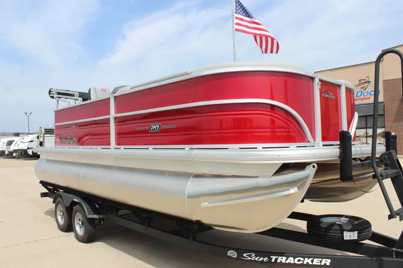 Slide: The Image of 2026 Sun Tracker Party Barge 20 DLX pontoon boat on trailer, American flag in background. - 3