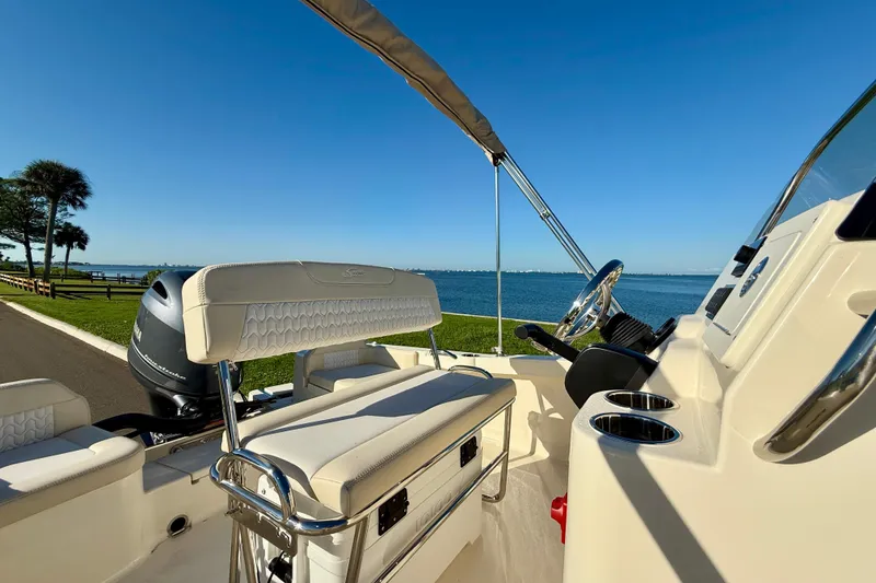 Slide: The Image of 2026 Scout 188 Sportfish boat interior with steering wheel, overlooking scenic waterfront. - 10