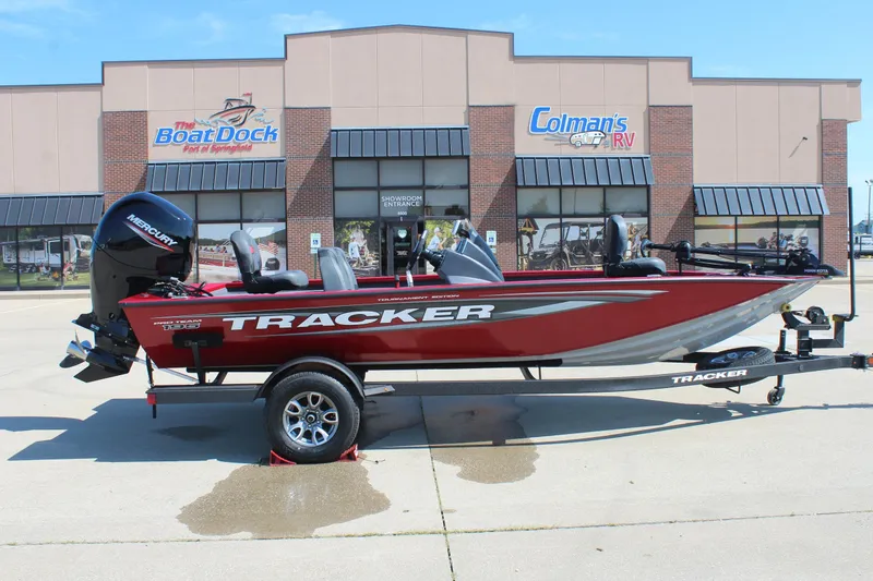 The Image of 2026 Tracker Pro Team 195 boat in red, parked outside dealership, with Mercury engine. - 1